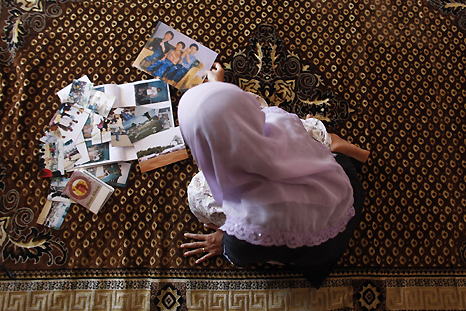 Another survivor, Dina Astita ,views family photographs at her home in Aceh, Indonesia. Dina lost her three sons in the wave which killed 90 per cent of her town’s inhabitants. REUTERS/Damir Sagolj