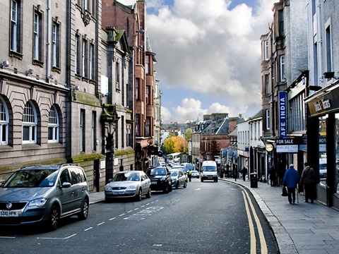 Colour view down New Street, Paisley, a mixed street of shops with offices and housing above.
