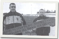 Derek Roberts, hyfforddwr ac Adie Jones, rheolwr, gydag un o'r arwyddion dwyieithog newydd.