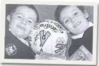 Dau o blant Ysgol Nefyn gyda'r bêl-droed wedi ei harwyddo gan aelodau o dîm Cymru.