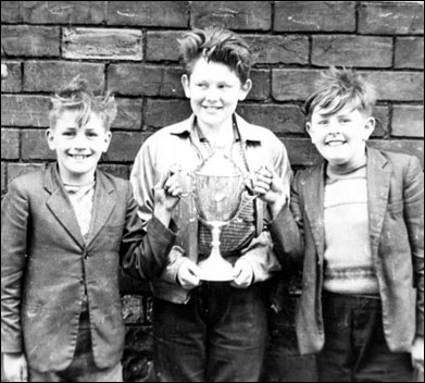 Three boys holding a trophy