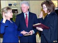 Hillary Clinton sendo empossada no cargo, com Bill Clinton segurando a Bíblia enquanto ela faz o juramento