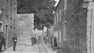 Black and white view of Albert Street, Kirkwall, showing wall surrounding the Big Tree.