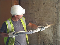 Workman lime-rendering the ecoDepot's straw panels