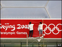 Trabalhadores substituem cartaz da Olimpíada pelo dos Jogos Paraolímpicos em Pequim