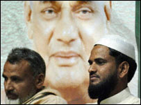 Eleitores muçulmanos passam diante de um cartaz do primeiro-ministro Vajpayee