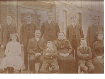 Llun fy nheulu o gyfnod 1910. Yn y cefndir gweler siop Corner Stores oedd yn berchen i'r teulu. Gwelir yma saith brawd a dwy chwaer.