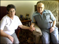 Ann and Keith holding hands on the sofa