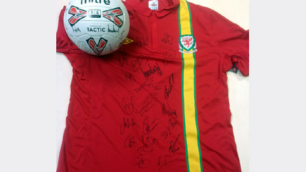 Crys a phêl wedi eu llofnodi gan dïm pel droed Cymru