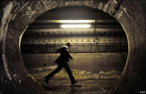 Một người đàn ông bước qua vũng nước trong đường hầm.