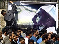 صفی از فلسطينيان که برای گفتن تسليت به رهبری حماس از کنار تصوير شيخ احمد ياسين عبور می کنند