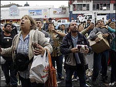 Ciudadanos en Concepción esperan que les arrojen víveres de un supermercado saqueado.