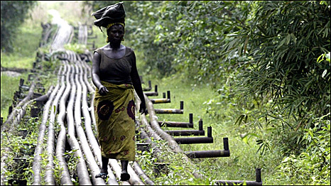 A Nigerian woman walks along an oil pipeline