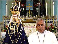 वर्जिन मेरी की मूर्ति के साथ पादरी