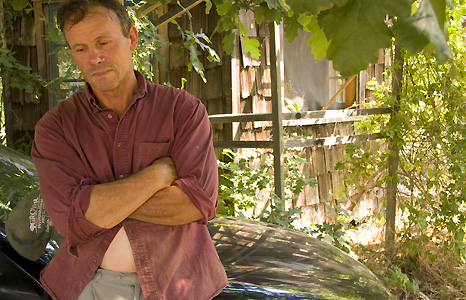 Man in red shirt leaning on car. Photograph by Alix Lowrey Blair.