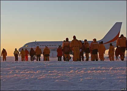 Các nhà khoa học, các quan chức chính phủ và phi hành đoàn bước trên đường băng tuyết.