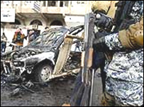 Irakieni uitându-se la carcasa distrusă a unei maşini