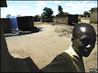 Muž stojí před jiným z táborů, na který povstalci zaútočili v roce 2003