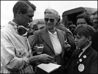 1956: British racing driver Peter Collins giving his autograph to a young fan after winning the Whitsun Trophy Race at Goodwood.