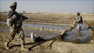 US soldier passes by an Afghan farmer