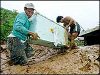 Filipinler'de iki afetzede eşyalarını kurtarmaya çalışıyor