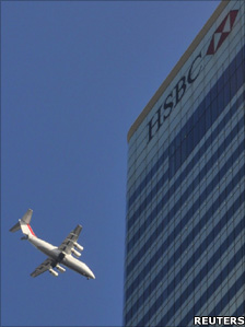 A plane flies past HSBC headquarters in London