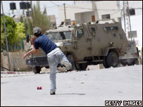 Jovem palestino joga pedras contra carro blindado israelense na Cisjordânia