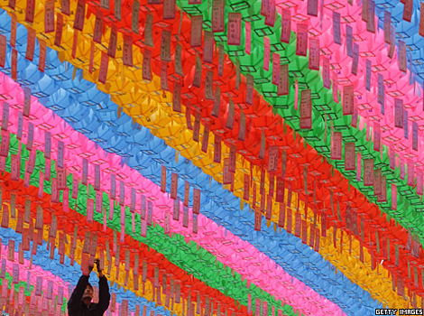 A Buddhist hangs colourful lanterns
