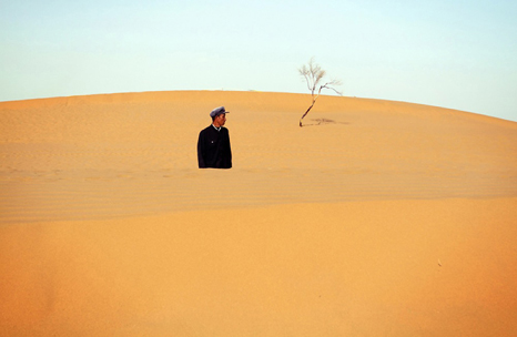 A farmer stands amongst the dunes of the Tengger Desert in Ningxia Province. 2009