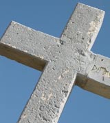 Heavy, square stone cross against bright blue sky