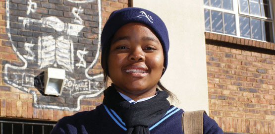 South African schoolgirl in uniform smiles at camera