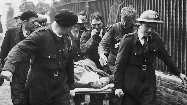 Mrs Bowley shakes the hand of Johnny Driscoll of the A.R.P. rescue team carrying her away. She had been trapped for 13 hours in the wreckage of an air-raid shelter after a German bombing raid on London, 17 October 1940.