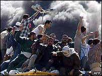 Iraquianos em caminhão passam por veículos queimados dos EUA