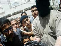 Maskeli bir Hamas militanı kanlı bir torbayı gösteriyor