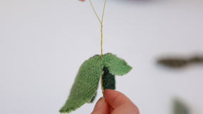 Hands holding leaf shapes made from fabric and thread