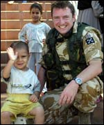 A child sitting on Ade's Helmet and waving