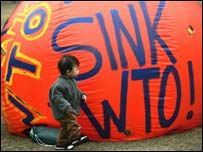 Criança em Hong Kong na frente de balão com os dizeres: 'Afunde OMC'