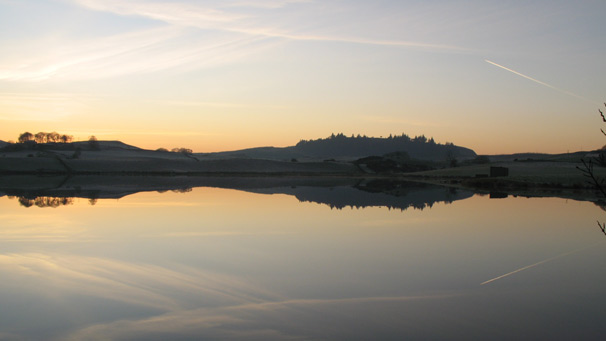 High cloud reflected in mirror-flat reservoir surface