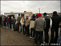 Pessoas que aguardam concessão de asilo fazem fila para distribuição de comida em Calais