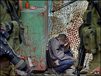 Soldados israelenses observam jovem palestino preso