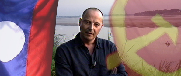 Chris Jackson by Mekong River with Lao and hammer and sickle flags