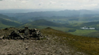 View from the top of Carn Liath showing the cairn at the summit and the surrounding hills.