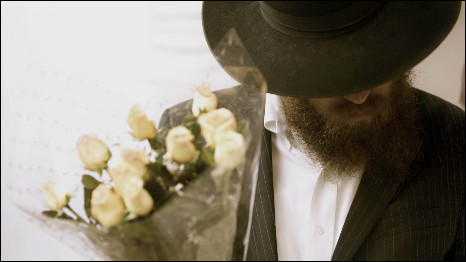 A Lubavitch mourner carrying flowers