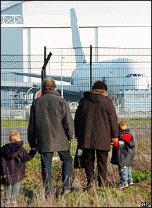 Rodina pozorující, jak dopravní letoun A 380 opouští hangár