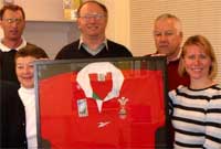 Aelodau'r pwyllgor gyda'r crys rygbi wedi'i fframio