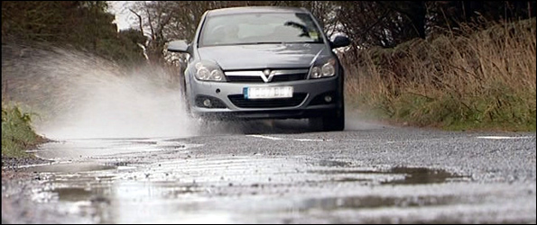 Car driving through water-filled potholes