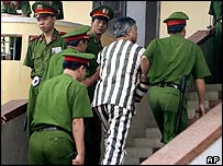 Ông Lương Quốc Dũng mặc áo tù trong lúc bị công an dẫn