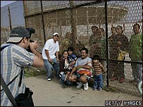 família fotografando ao lado da fronteira americana com o México