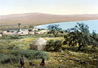 Middle Eastern landscape with sparse grass and trees, ancient buildings and people in traditional dress sitting in the foreground