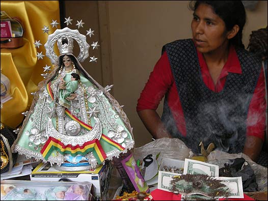 Una vendedora junto a una escultura de una virgen